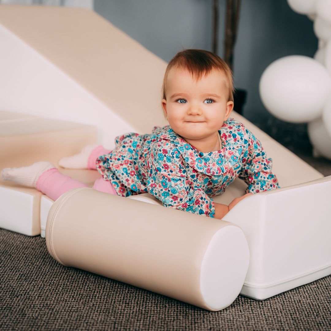 Smiling baby playing on soft beige Explorer blocks indoors