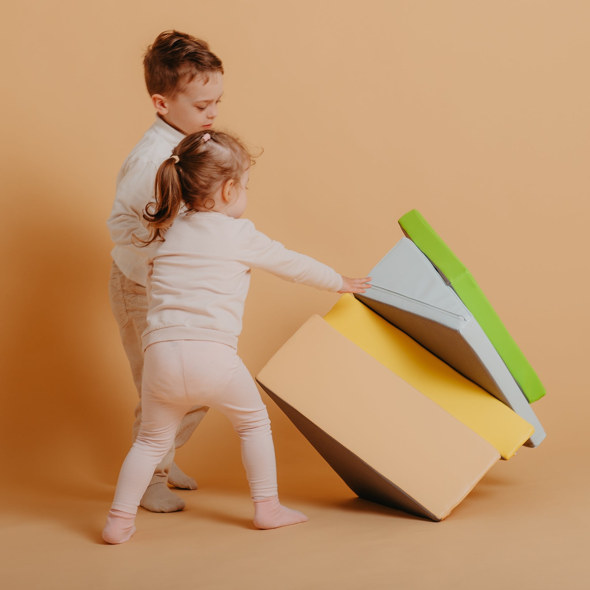 Toddler carrying lightweight Kubo Blocks Lumo foam play blocks independently during active play