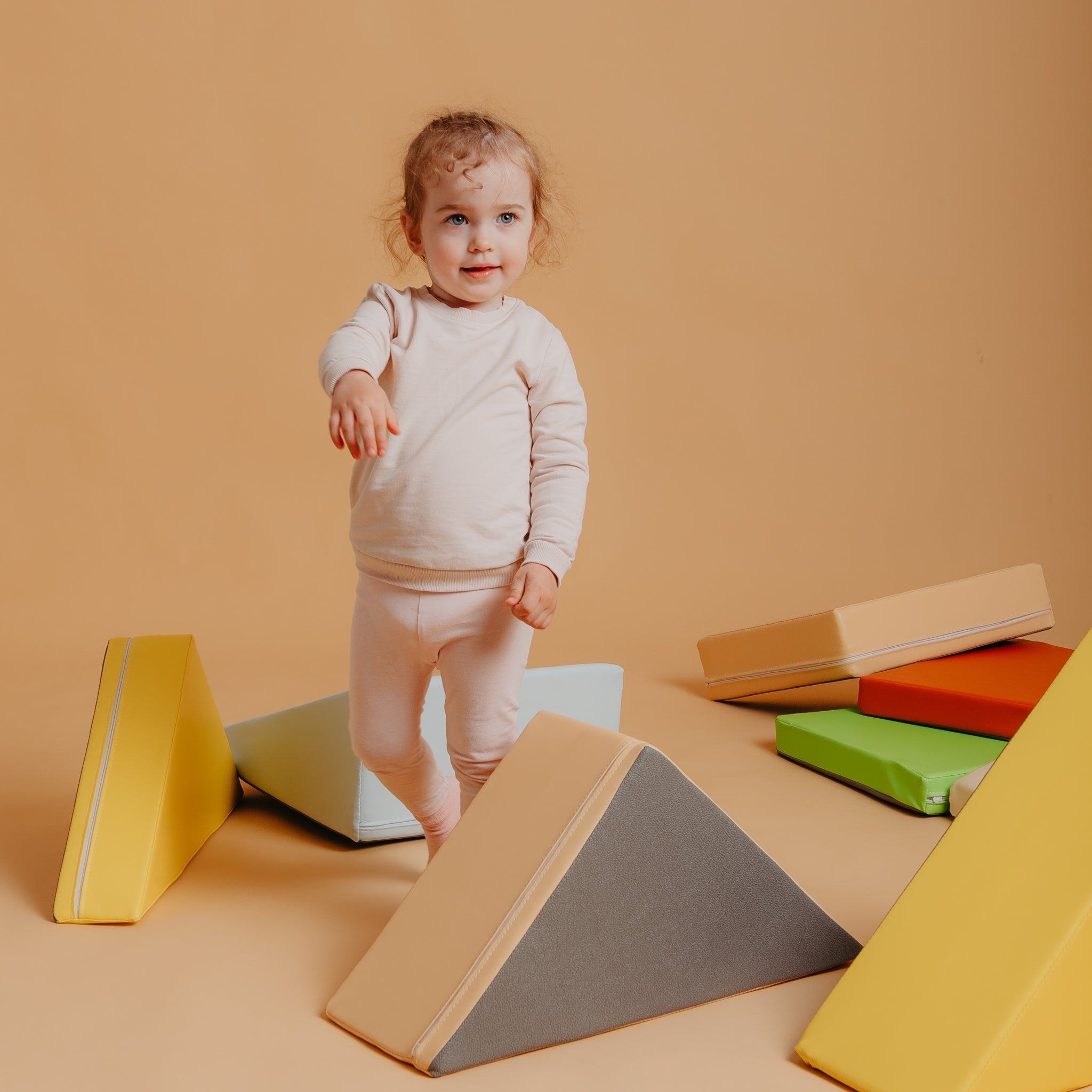 Toddler playing with Kubo Blocks Lumo orange soft play set for sensory exploration and active indoor play