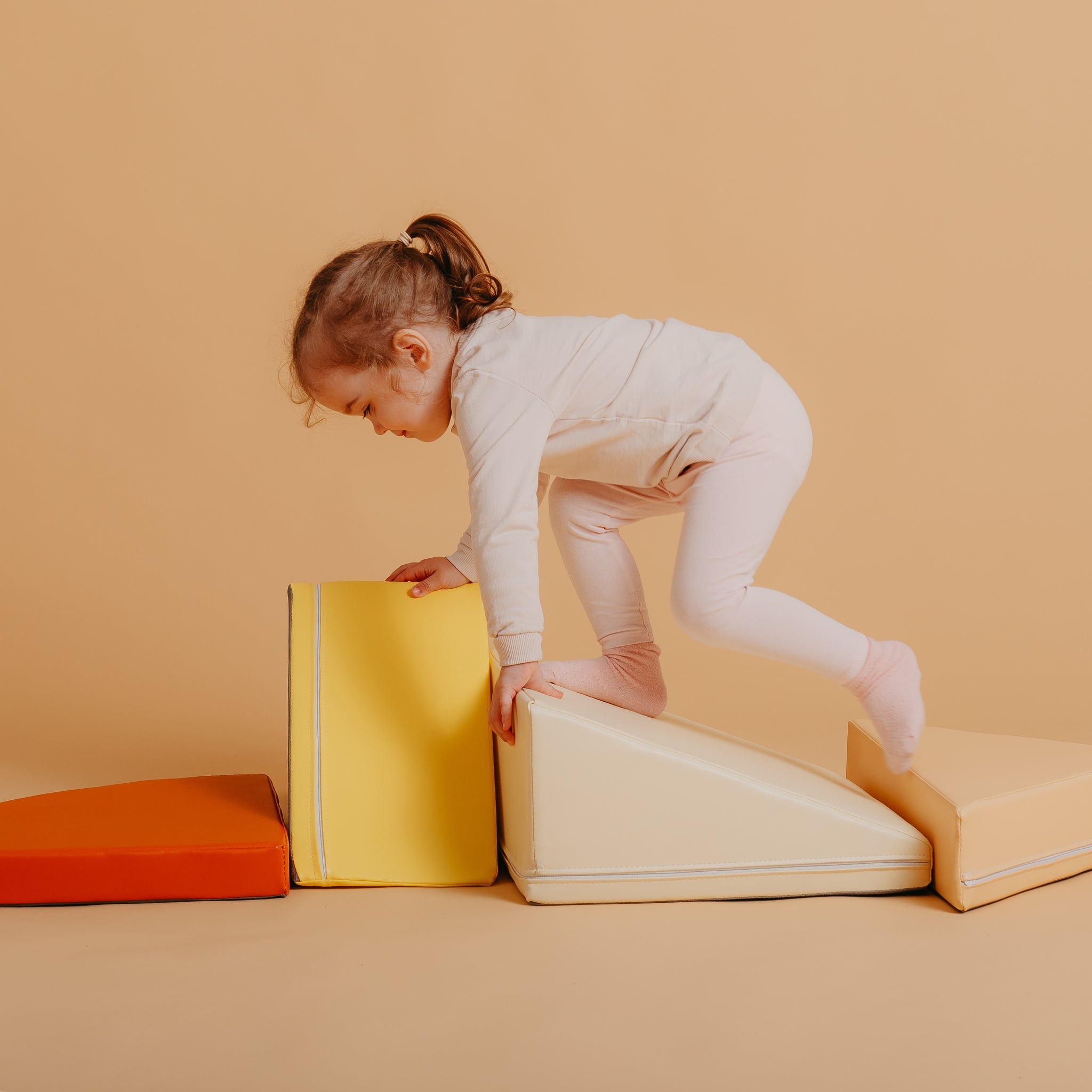 Toddler climbing on Kubo Blocks Lumo soft play blocks designed for gross motor skill development