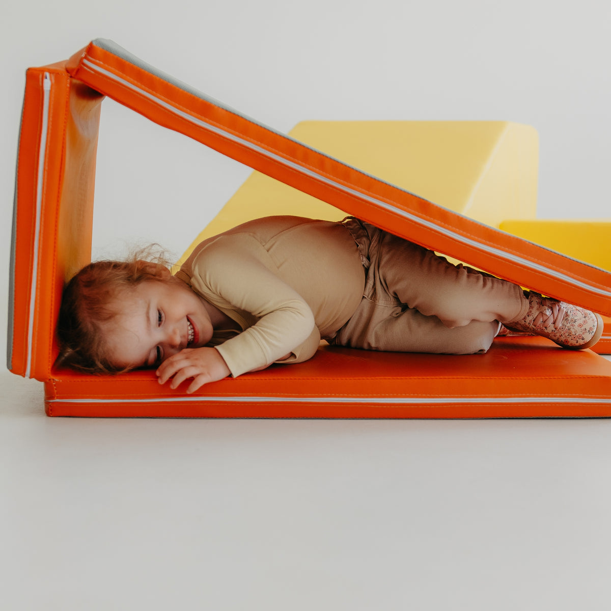 Child resting inside a cosy play space made with the Kubo Blocks MATO foldable mat
