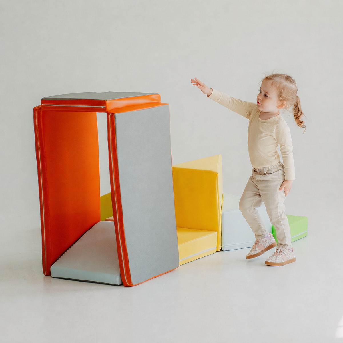 Child creating different soft play shapes with the orange Kubo Blocks MATO foldable play mat