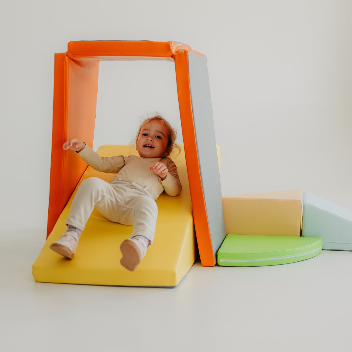 Child playing on a slide created with the Kubo Blocks MATO foldable foam play mat