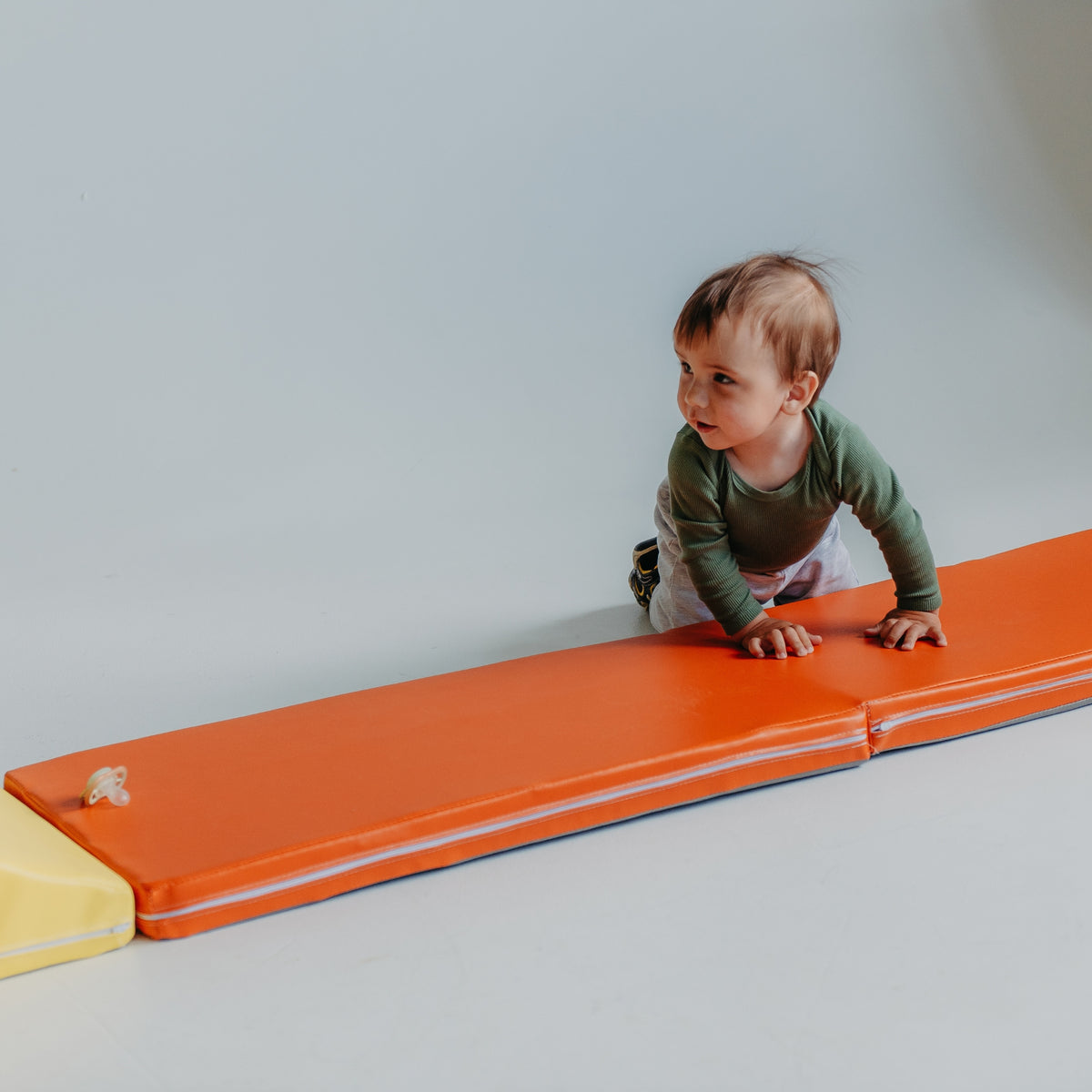 Child sitting on the orange Kubo Blocks MATO foldable kids play mat