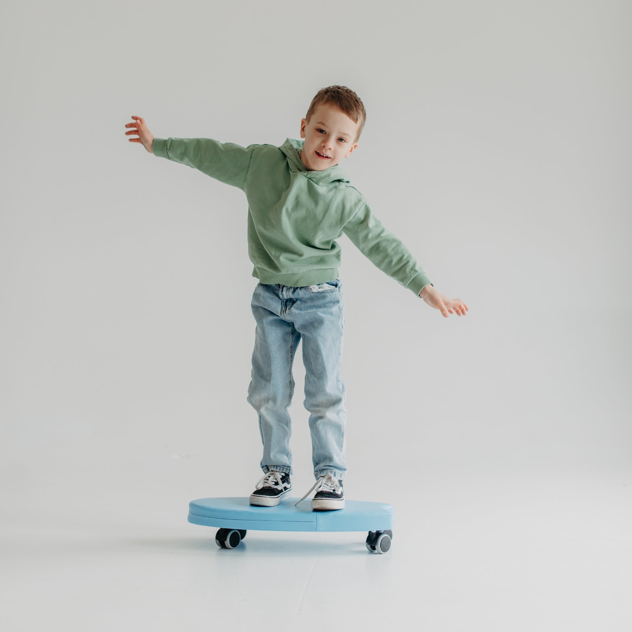 Child balancing on blue foam surf ride on toy, indoor soft ride-on toy for balance and play