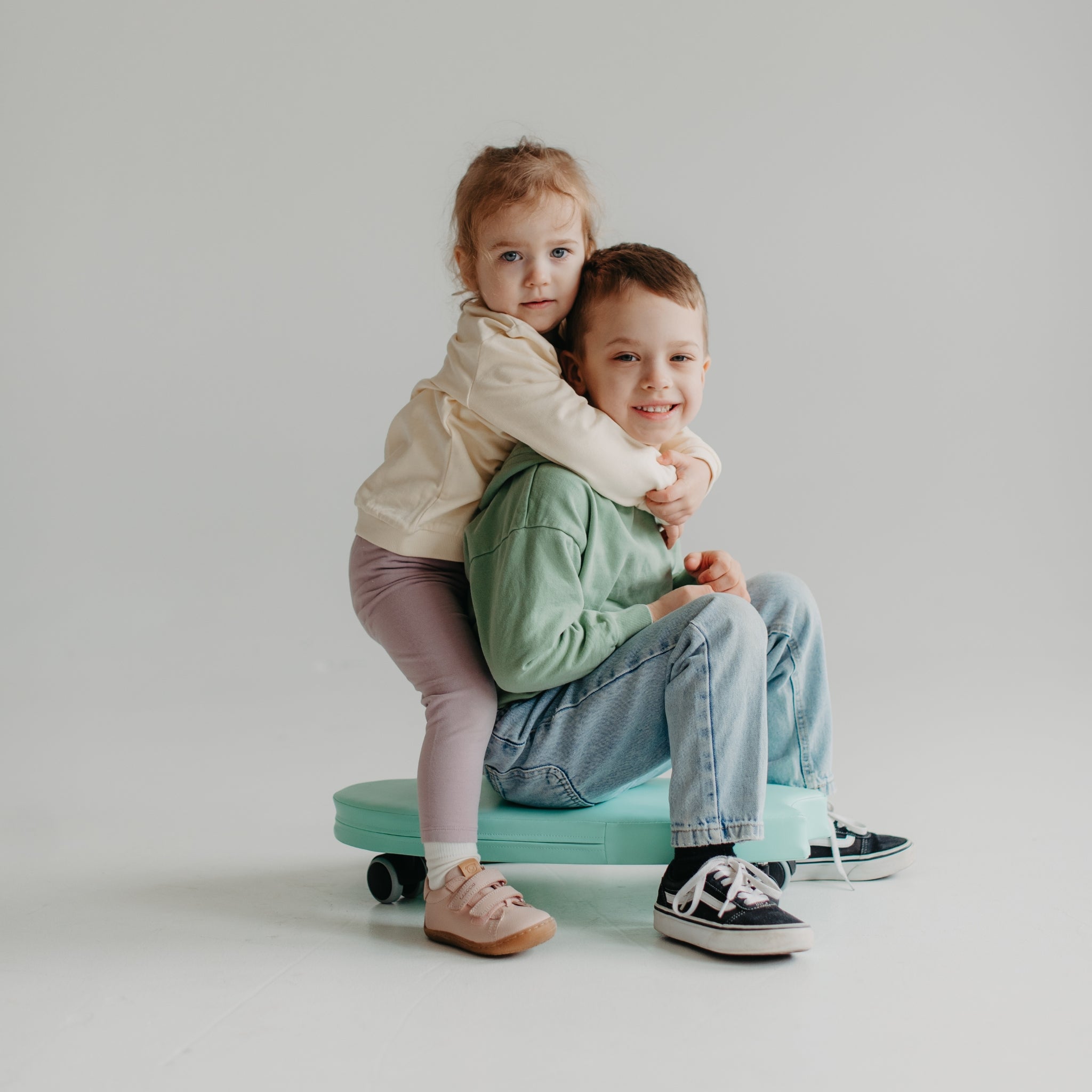 Toddler sitting on green foam ride on toy, safe indoor soft play toy with wheels