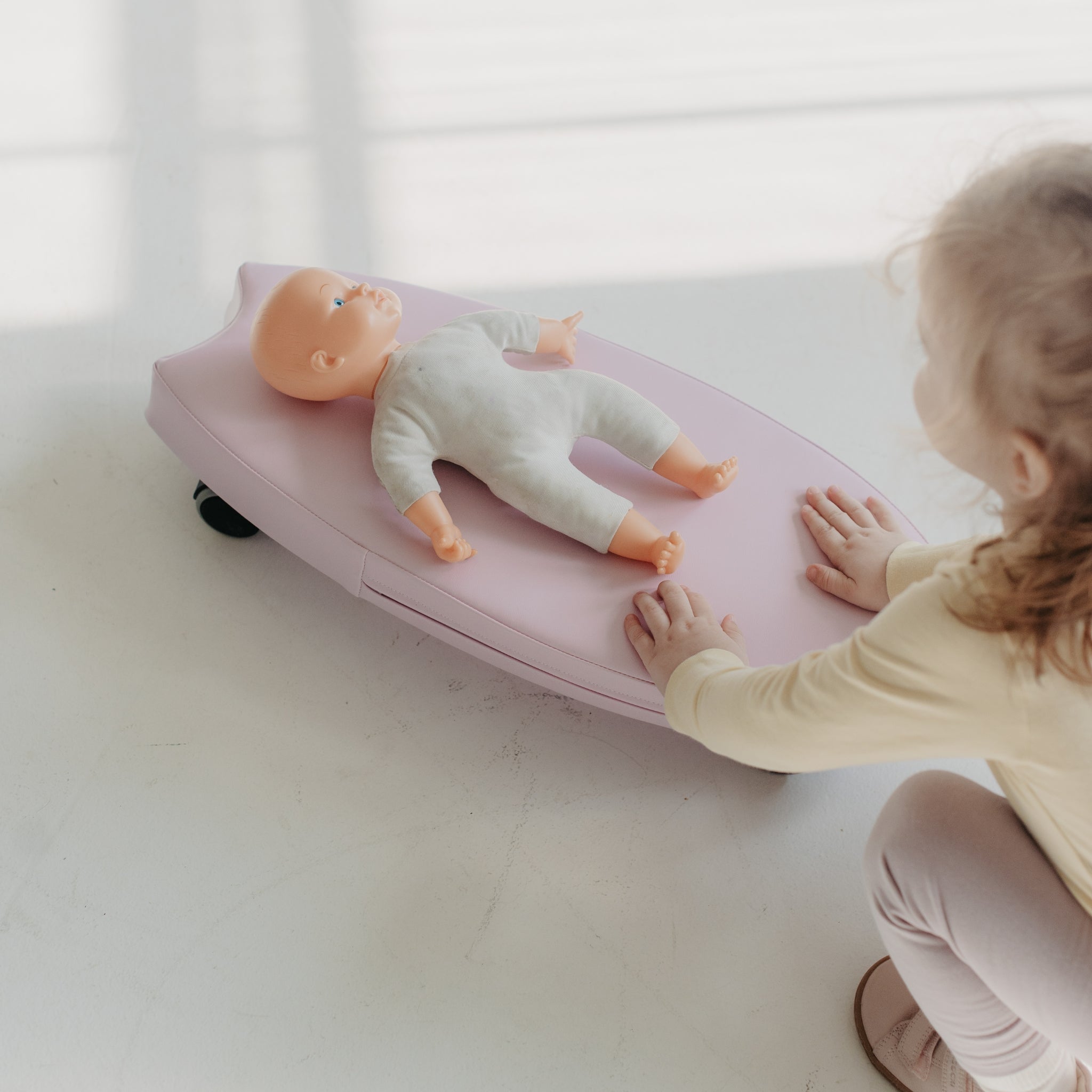 Foam surf ride on toy in pink with child playing, soft indoor ride-on board used for pretend play with doll