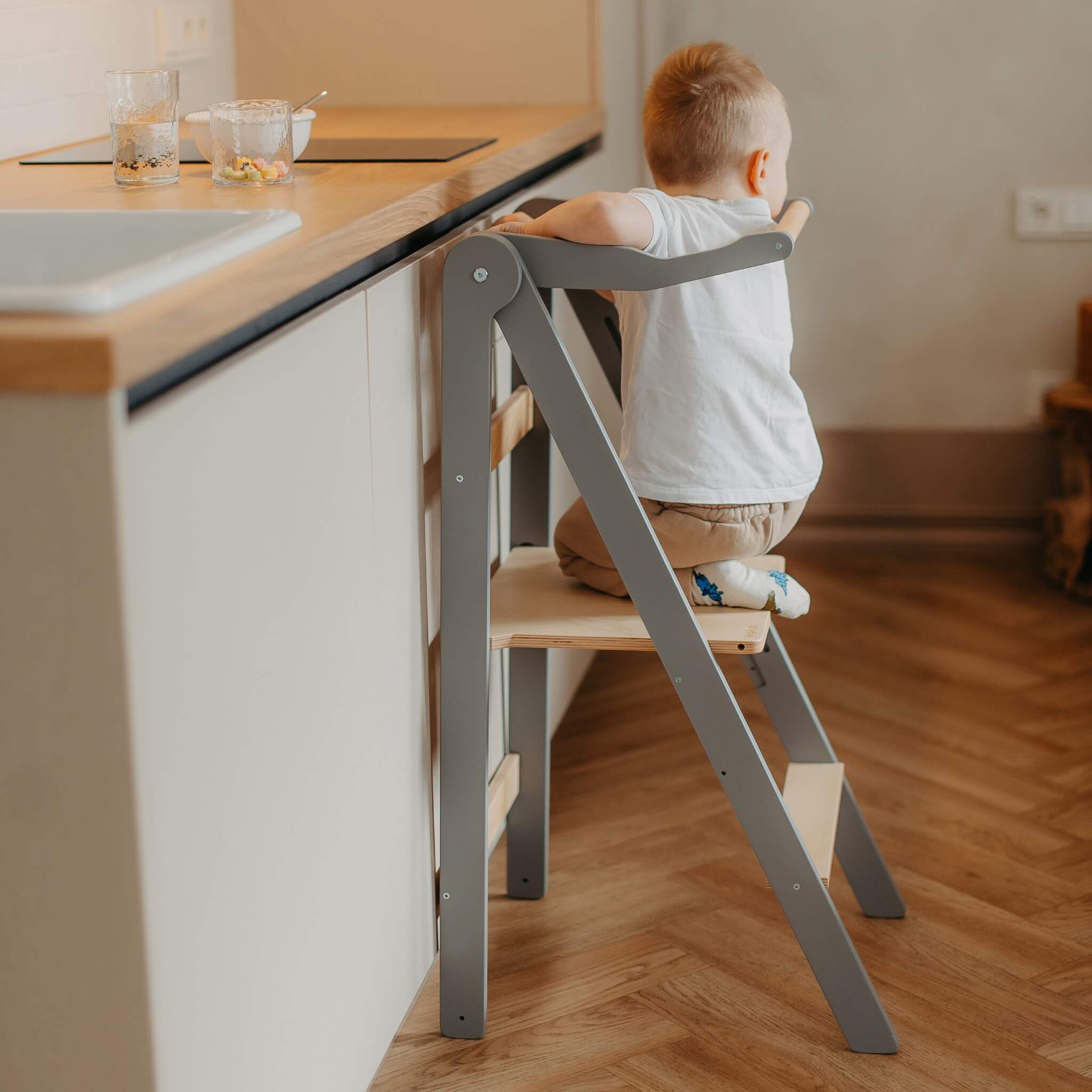 Toddler climbing onto foldable learning tower with secure step design