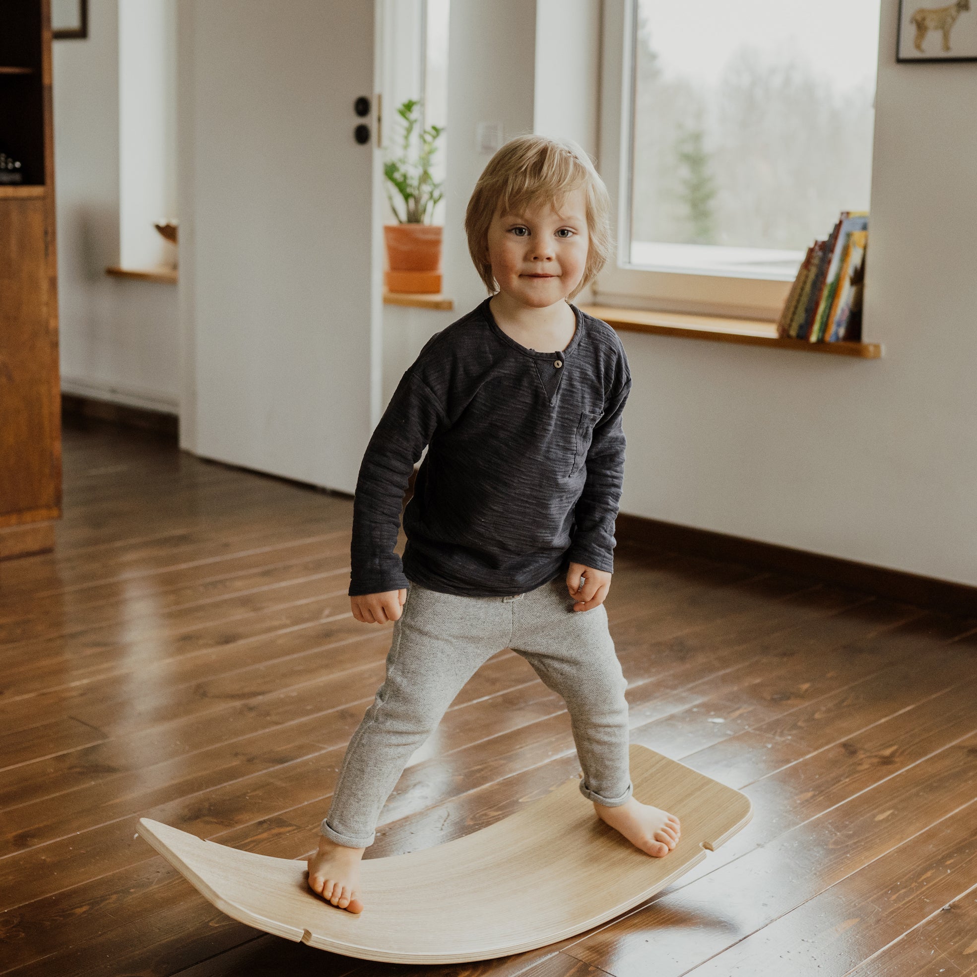 Toddler playing on wooden balance board indoors