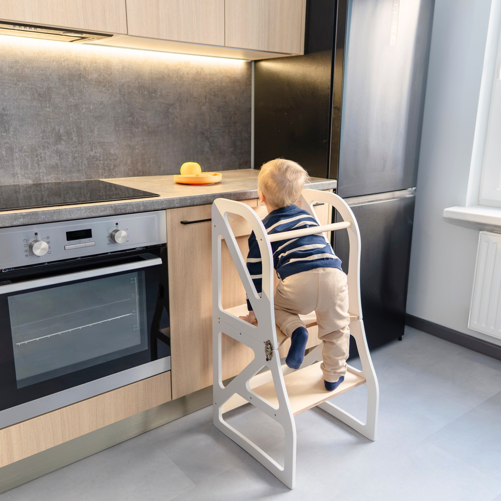 Convertible kitchen tower used as toddler step stool at kitchen counter