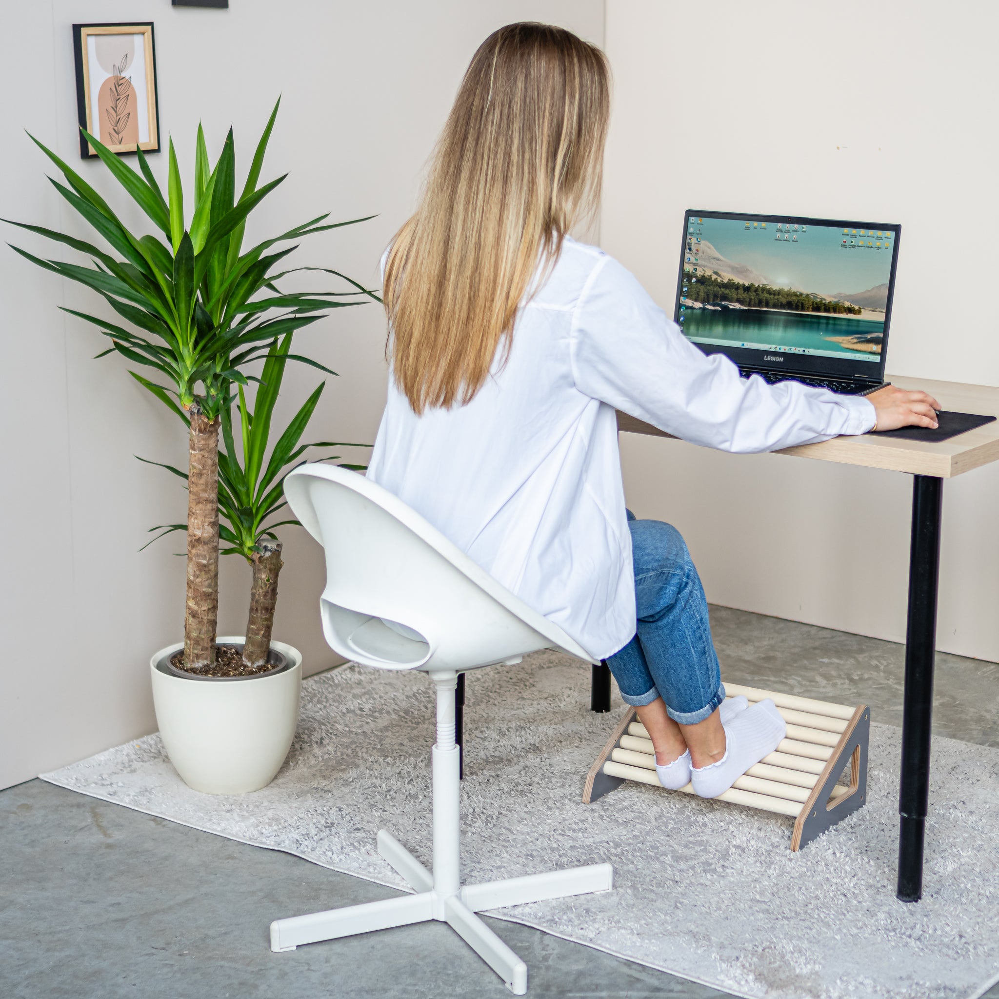 Woman using a wooden footrest roller while working at a home office desk