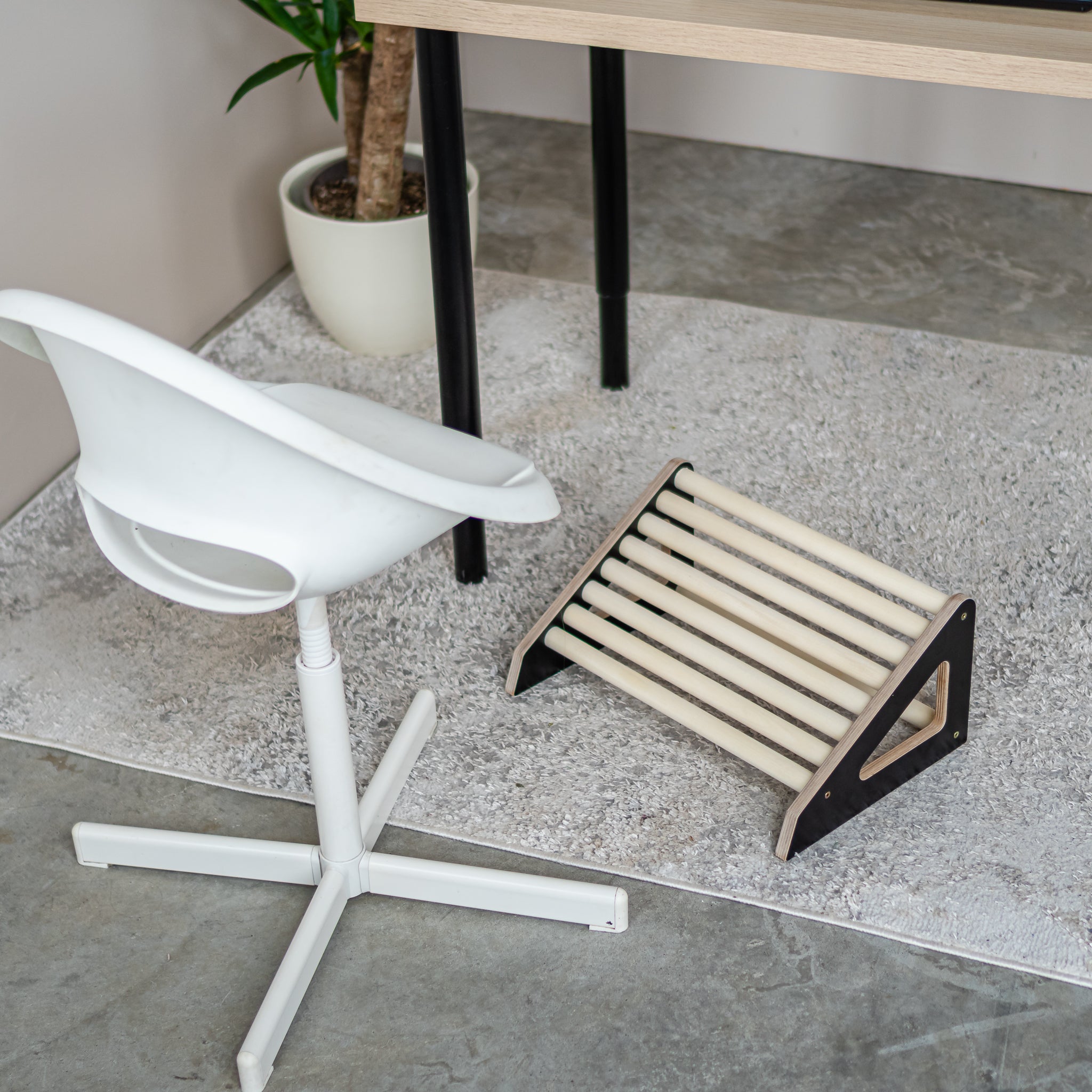 Side view of ergonomic wooden footrest roller for office use